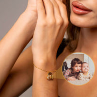 Thumbnail for A close-up of a woman's wrist wearing the Family Photo Bracelet by Brother & Sisters, featuring a photo pendant of children.