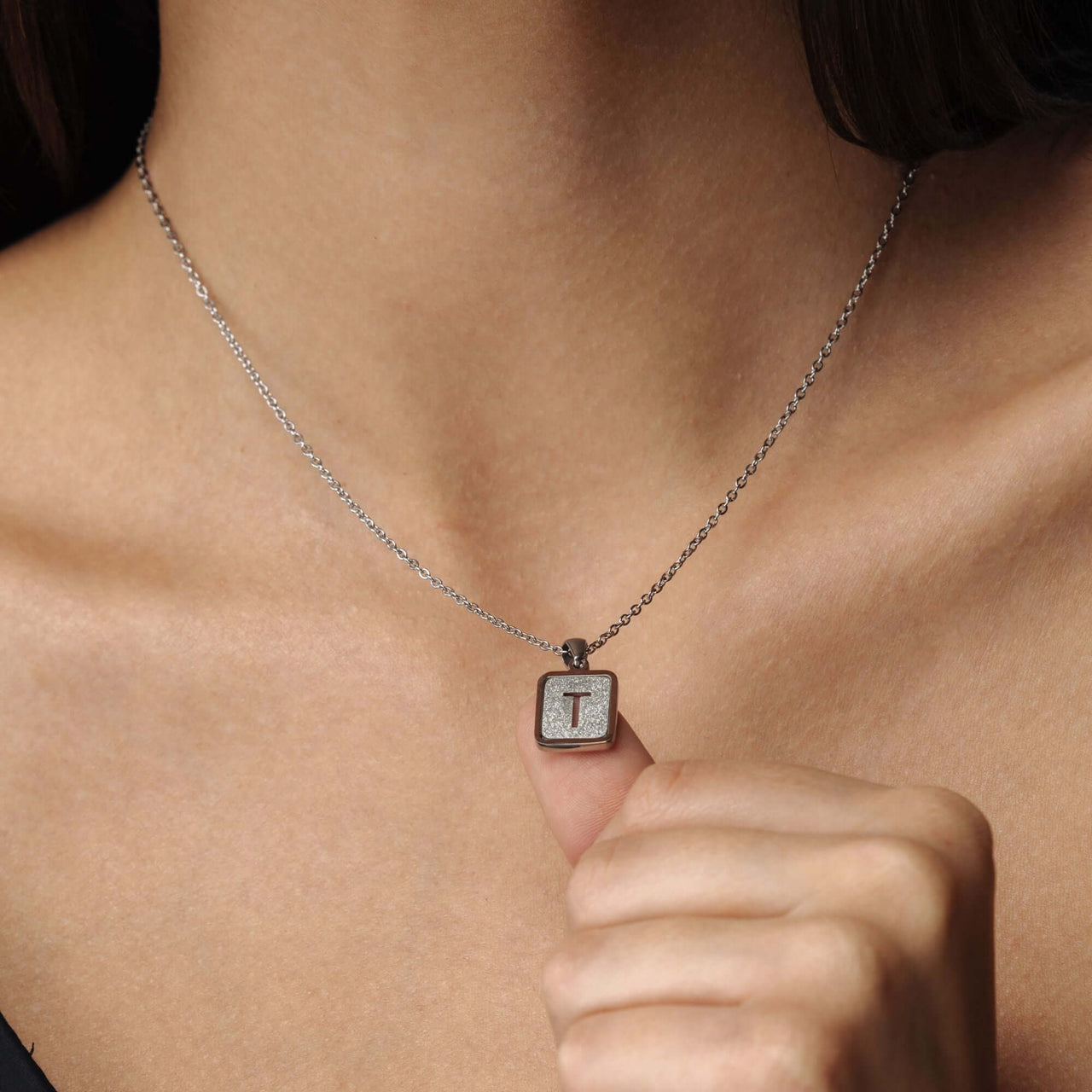 Glitter Initial Necklace by Brother & Sisters on a woman, showcasing a sparkling letter 'T' charm.