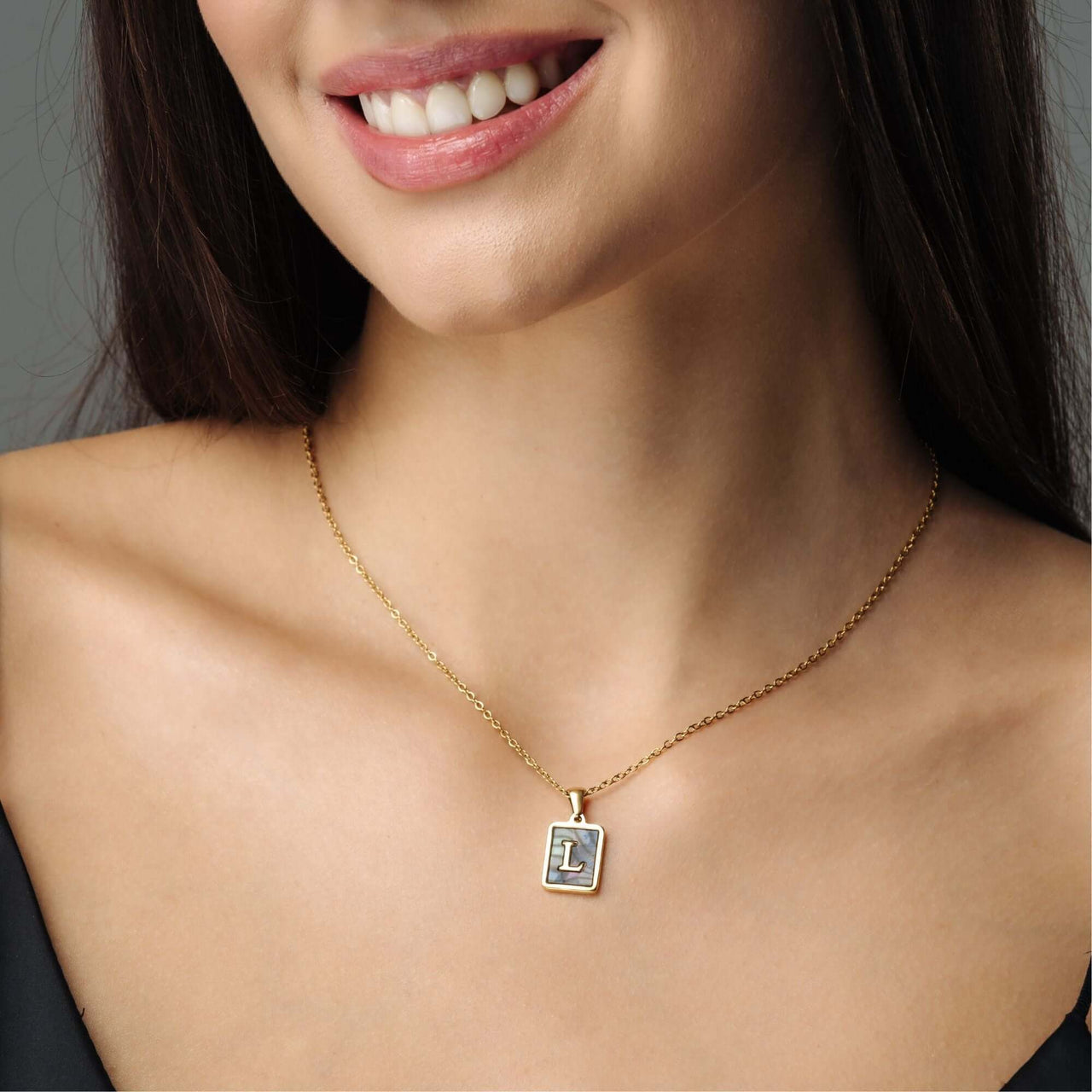 Happiness Initial Necklace shown on a model, featuring a gold pendant with the letter L, by Brother & Sisters.
