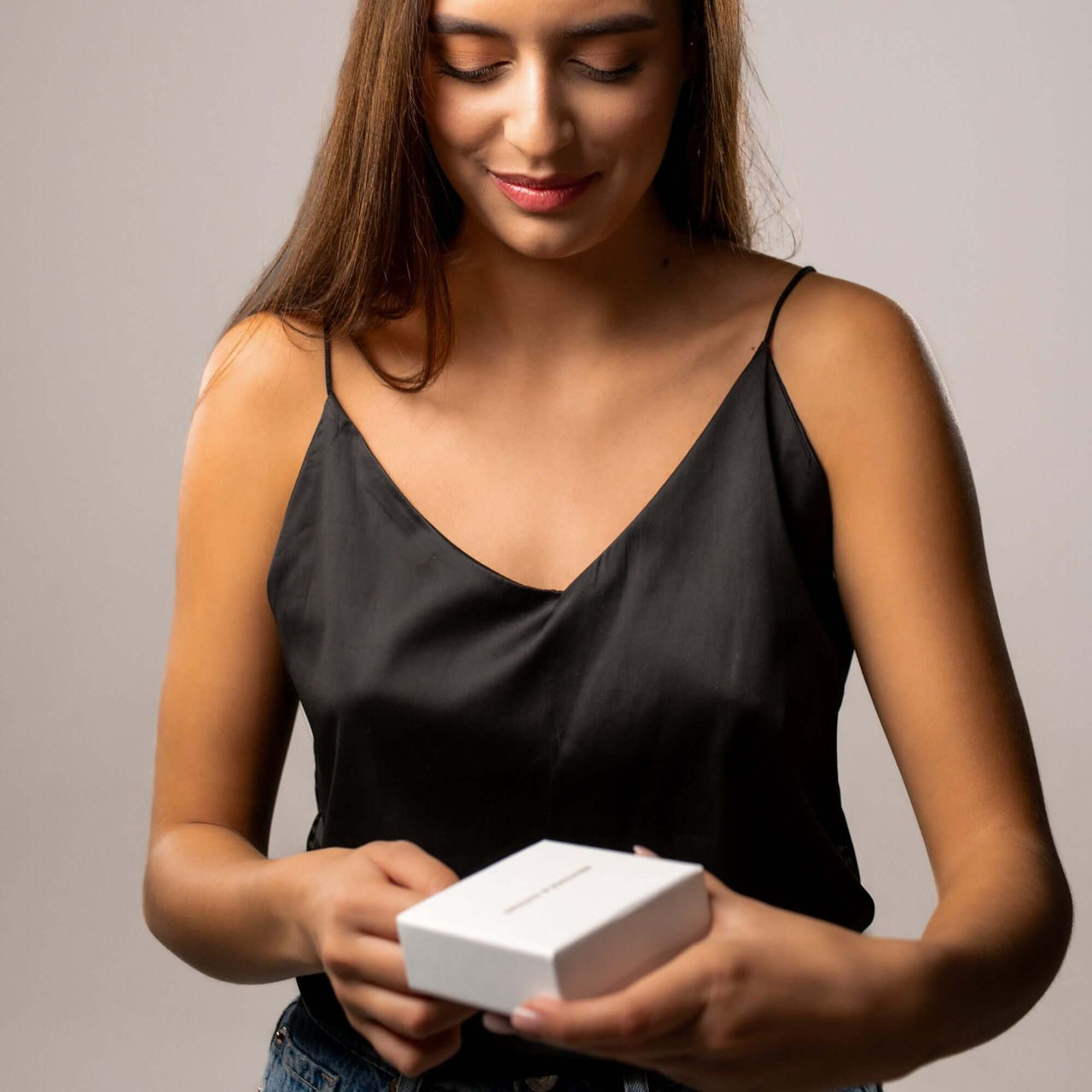 Woman opening a gift box, showcasing the Drop Photo Necklace by Brother & Sisters, designed for cherished memories.