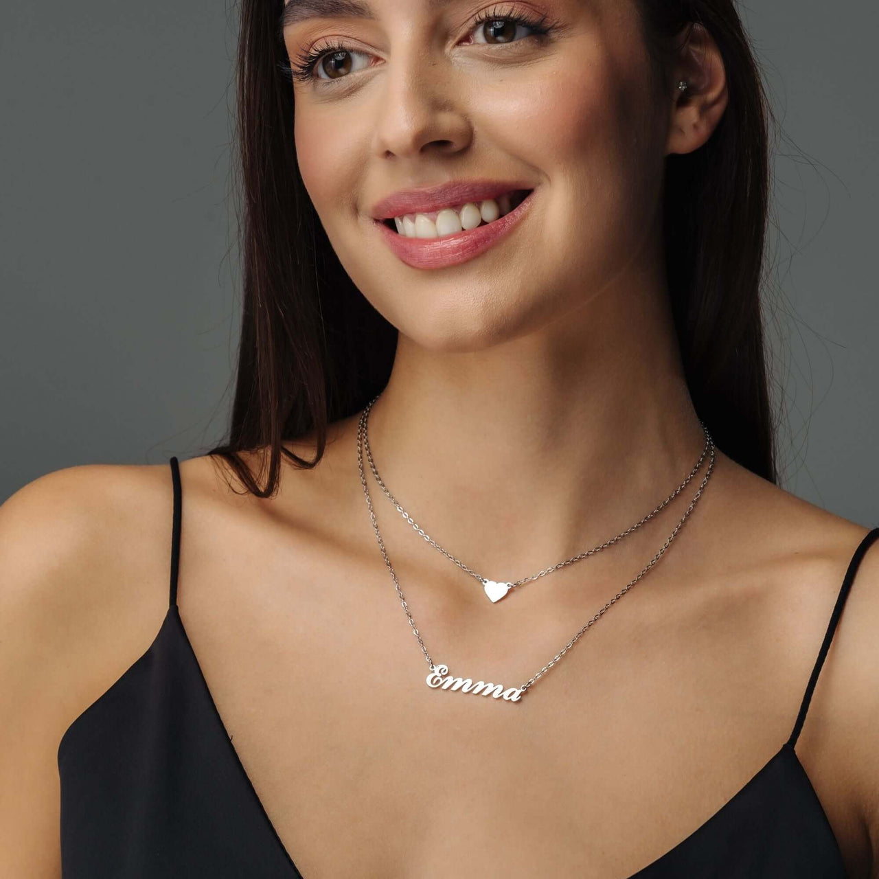 Heart Name Necklace worn by a smiling woman, featuring a custom nameplate and heart charm, by Brother & Sisters.