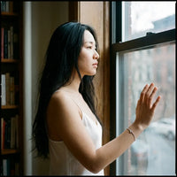 Thumbnail for Chinese woman by Brooklyn brownstone window wearing Her silver Heart Bond bracelet