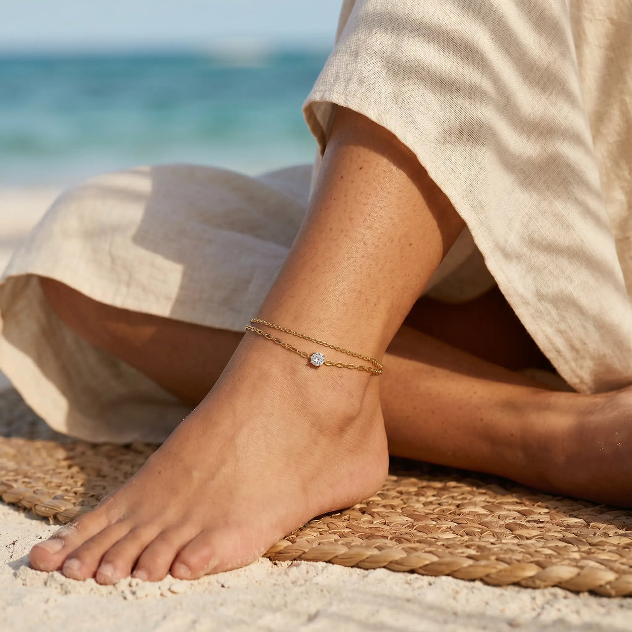Amalfi Layered Anklet on Mexican Latina ankle cross-legged on raffia rug in Tulum jungle beach — bohemian summer aesthetic with palm shadows
