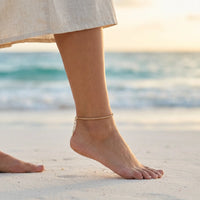 Thumbnail for Maëlle delicate gold tube-mesh anklet on Mexican Latina ankle walking on Tulum white powder sand beach at golden hour sunset — refined bohemian summer