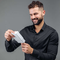 Thumbnail for Man in a black shirt smiling while holding a gift box, showcasing the Minimalist Photo Bracelet by Brother & Sisters.