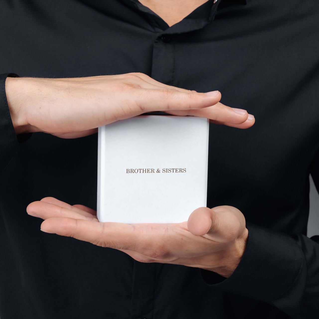 Gold Cube Initial Necklace packaging held by hands from Brother & Sisters, showcasing stylish and meaningful jewelry.