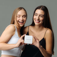 Thumbnail for Two women joyfully showcasing a Minimalist Name Necklace box by Brother & Sisters, highlighting personalized elegance.