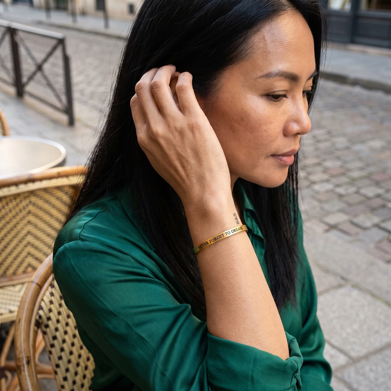 Woman gently touching her Never Forget To Dream bracelet in gold | SKU: nftd-g