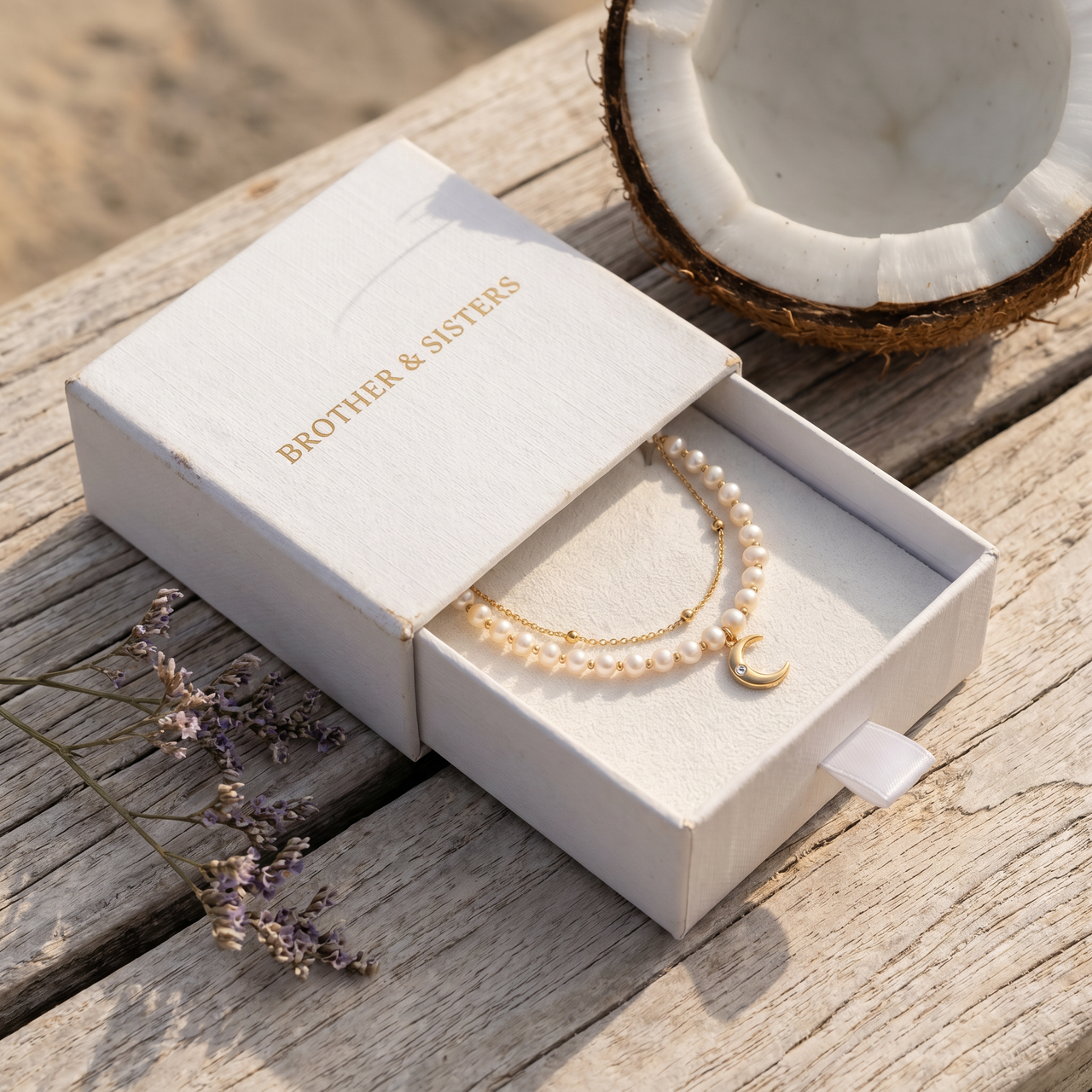 Brother & Sisters Pearl Moon Anklet Set in box with delicate pearls, crescent moon, and floral accents, embodying luxury.