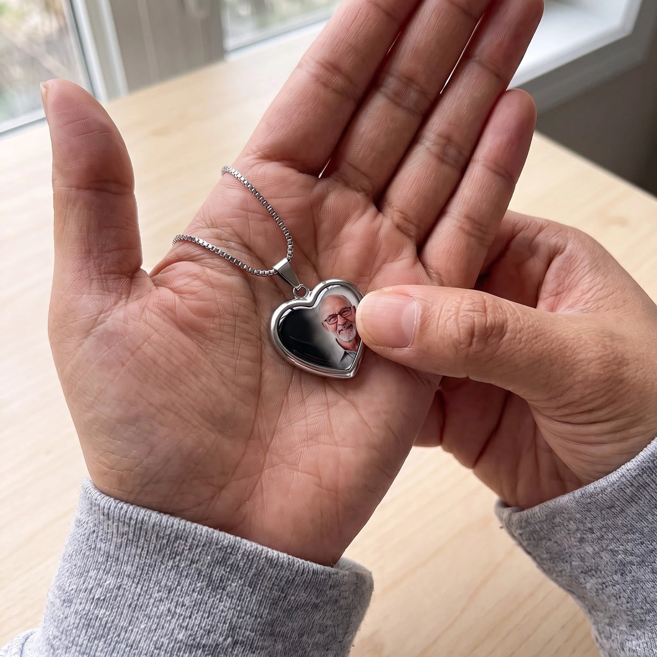 Thumb warming the silver heart pendant: the hidden photo appears under the thumb while the rest stays black | SKU: TPH-CHTN-SILVER-SMALL