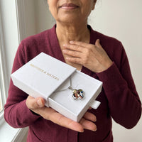 Thumbnail for Woman in a burgundy cardigan holding the Brother & Sisters gift box with the silver clover photo necklace inside | SKU: TPH-CLVN-SILVER