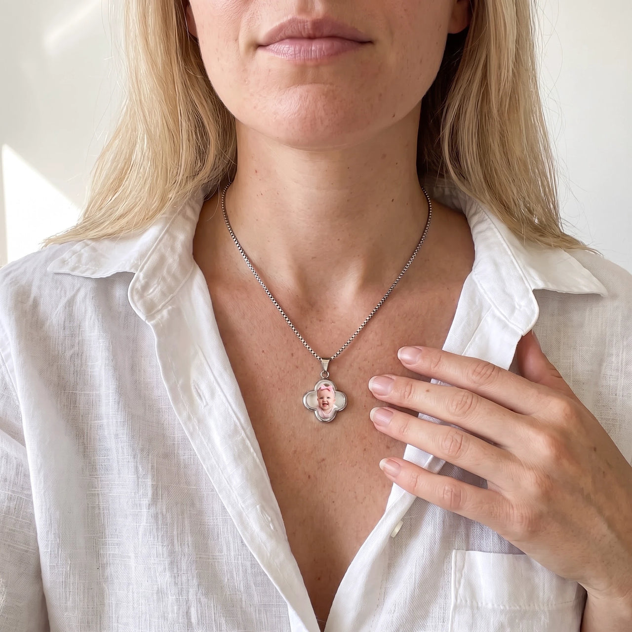 Blonde woman in a white shirt, hand on her chest, wearing the silver secret clover photo necklace | SKU: TPH-CLVN-SILVER