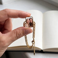 Thumbnail for The gold cushion-cut photo charm held between two fingers, showing its real small size with a photo of two best friends laughing together | SKU: TPH-CUSB-GOLD