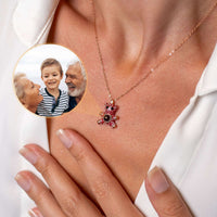 Thumbnail for Teddy Bear Photo Necklace showing a woman wearing a sentimental projection jewelry with a family photo in the background.