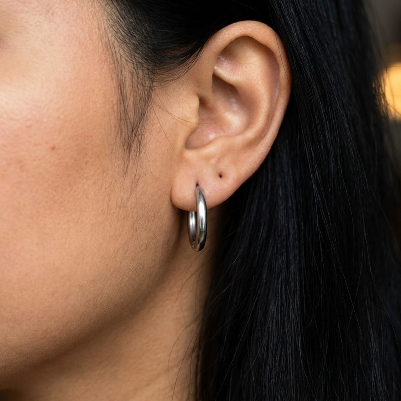 Tiny Huggie Hoops in Silver, close-up on the earlobe | SKU: 41002-silver