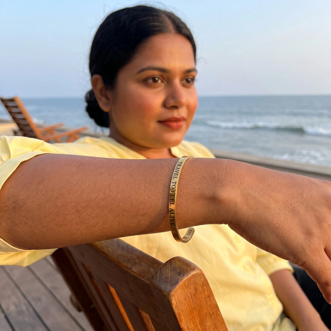 Travel To Feel Alive bracelet in gold worn during a relaxed moment | SKU: ttfa-g