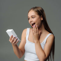 Thumbnail for Young woman excitedly opening a gift box, showcasing surprise and joy.